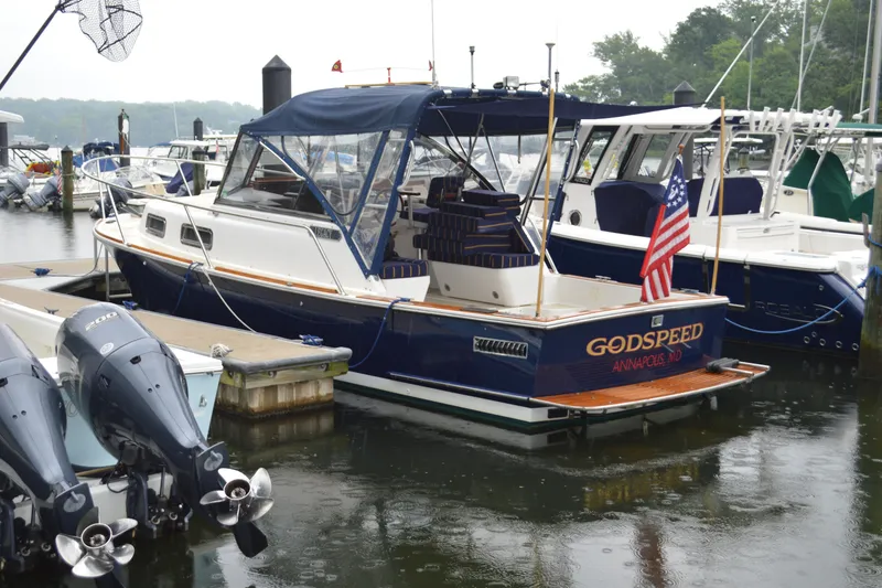 Slide: The Image of 2003 Legacy 28 Express boat docked, featuring blue canopy and American flag. - 3