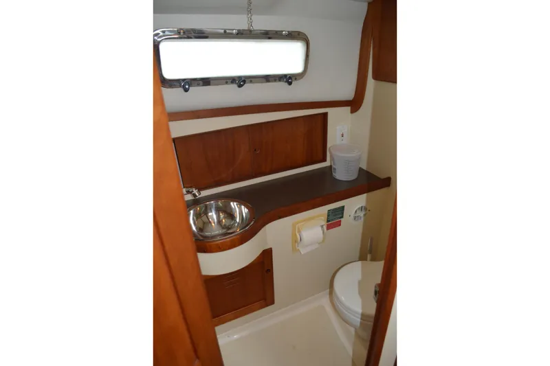 Slide: The Image of 2003 Legacy 28 Express boat bathroom with sink, toilet, and wooden cabinetry. - 10