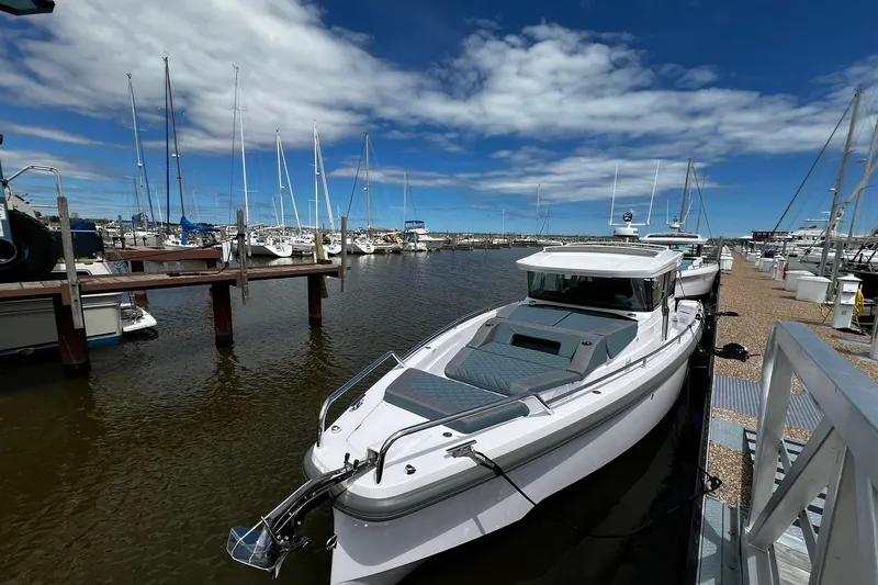 Slide: The Image of 2025 Axopar 37 XC Cross Cabin docked at a marina under a blue sky. - 1