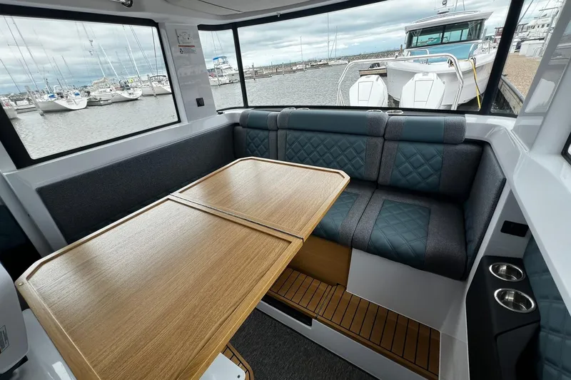 Slide: The Image of Interior of 2025 Axopar 37 XC Cross Cabin with seating and table, docked at marina. - 14