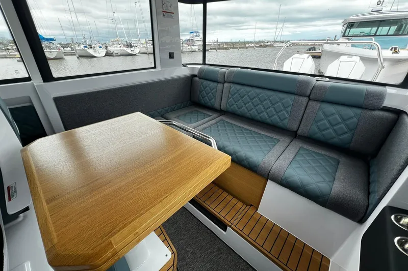 Slide: The Image of 2025 Axopar 37 XC Cross Cabin interior with cushioned seating and wooden table. - 15