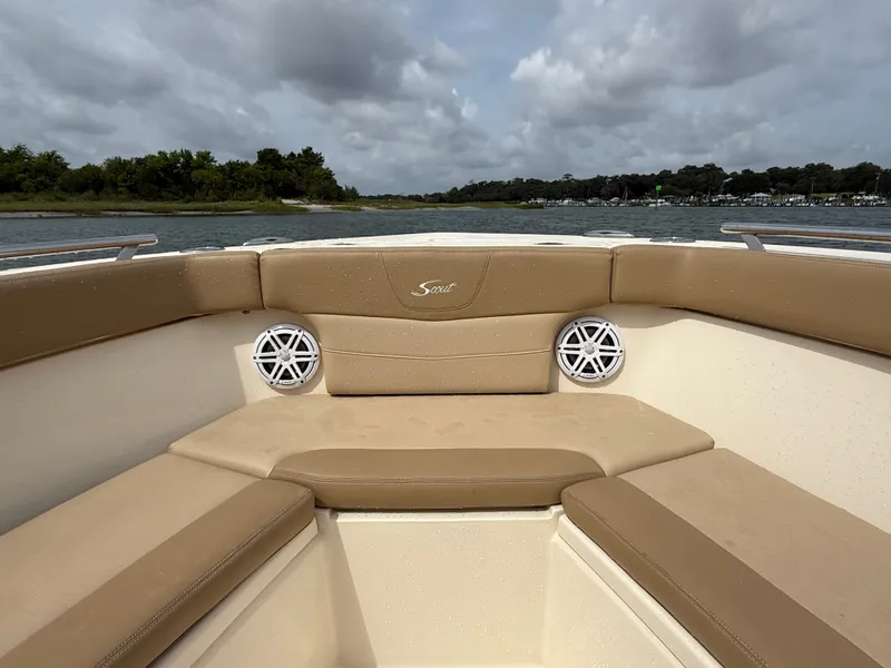 Slide: The Image of The image shows the bow area of a Scout 235 XSF boat with beige cushions and speakers. - 19