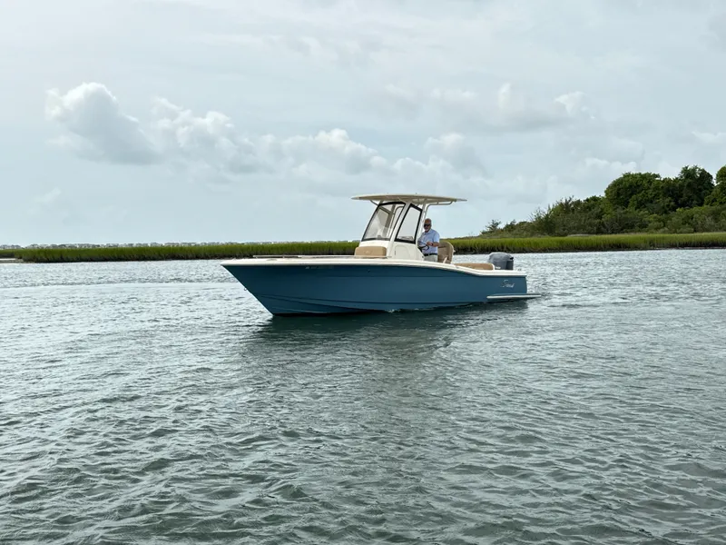 Slide: The Image of A 2020 Scout 235 XSF boat on calm water with a cloudy sky in the background. - 7