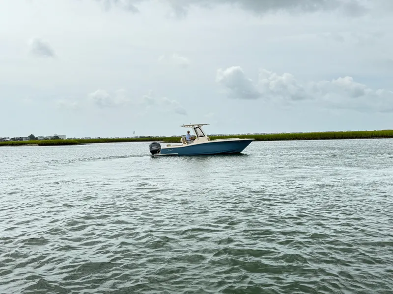 Slide: The Image of A 2020 Scout 235 XSF boat cruising on calm waters with a cloudy sky in the background. - 4