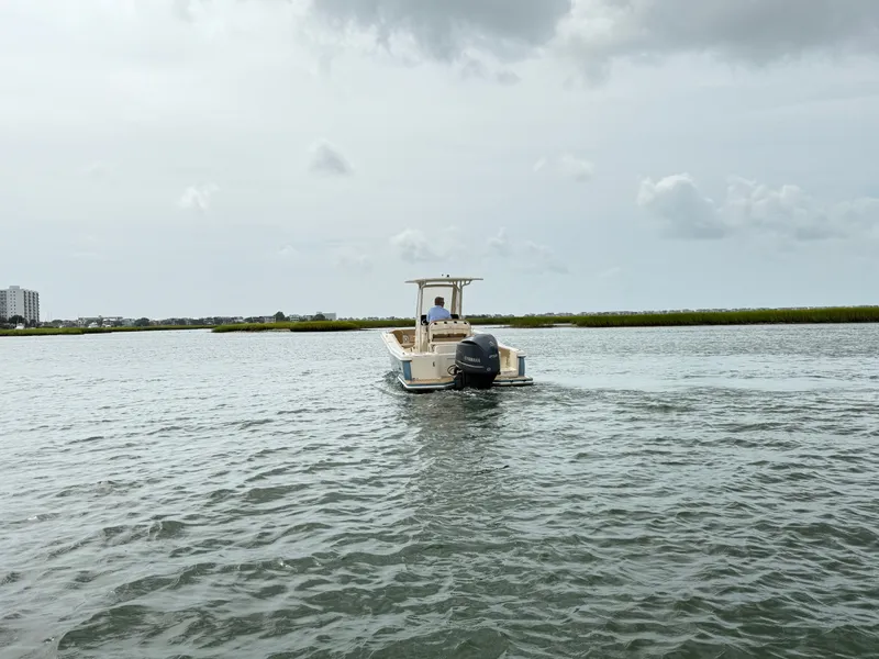 Slide: The Image of A 2020 Scout 235 XSF boat cruising on calm waters under a cloudy sky. - 2