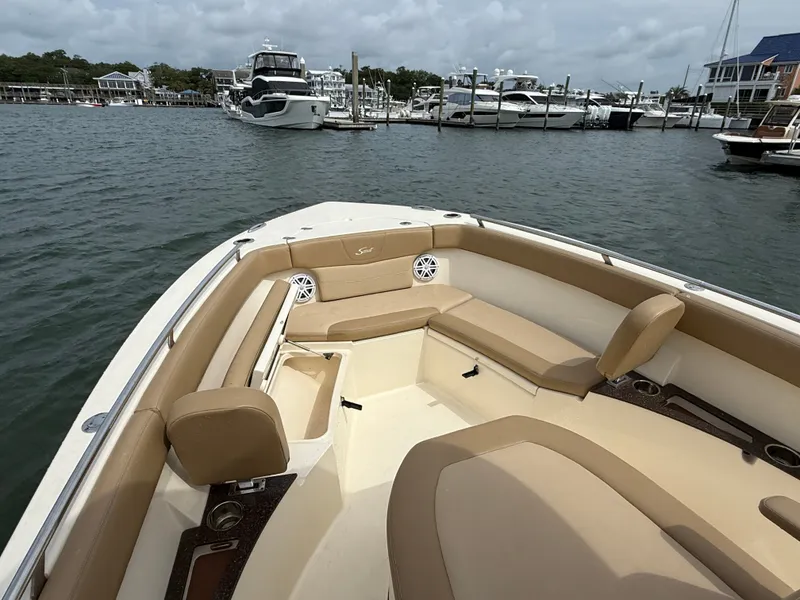 Slide: The Image of The image shows the bow of a 2020 Scout 235 XSF boat with beige seating, docked in a marina. - 20