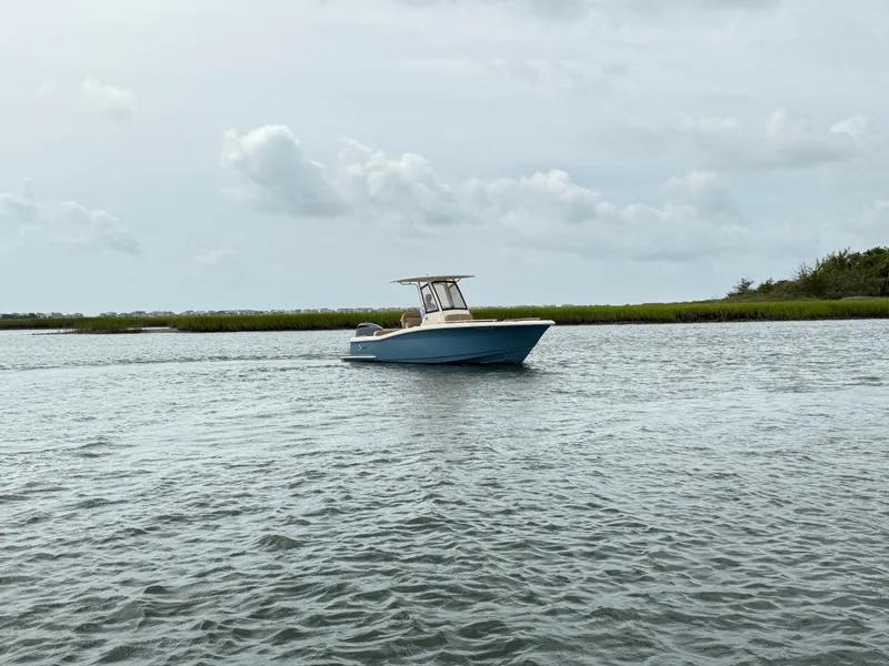 Slide: The Image of A 2020 Scout 235 XSF boat on calm water with a green shoreline in the background. - 5