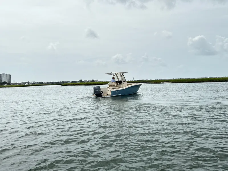 Slide: The Image of A 2020 Scout 235 XSF boat on calm water with a cloudy sky in the background. - 3