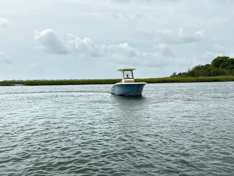 Slide: The Image of A 2020 Scout 235 XSF boat cruising on calm waters under a cloudy sky. - 6