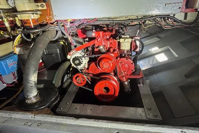 Slide: The Image of Engine compartment of a 1963 Rhodes 50, featuring a red mechanical engine with visible belts and hoses. - 37