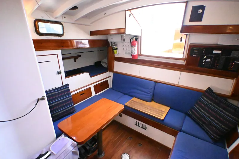 Slide: The Image of Cozy interior of a 1963 Rhodes 50 sailboat with blue seating and wooden accents. - 28