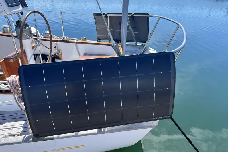 Slide: The Image of Solar panel on a 1963 Rhodes 50 sailboat, docked on calm water. - 10