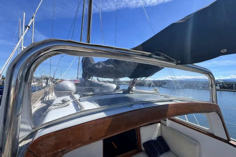 Slide: The Image of 1963 Rhodes 50 sailboat cockpit with clear canopy, docked under blue sky. - 11