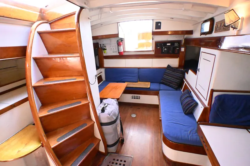 Slide: The Image of Interior of a 1963 Rhodes 50 sailboat with wooden stairs and blue seating. - 27