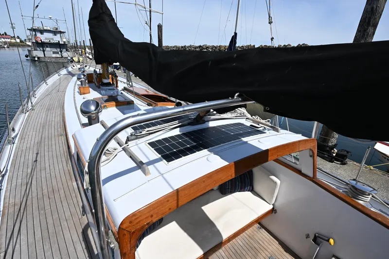 Slide: The Image of 1963 Rhodes 50 Cutter sailboat docked, featuring wooden deck and solar panel. - 19