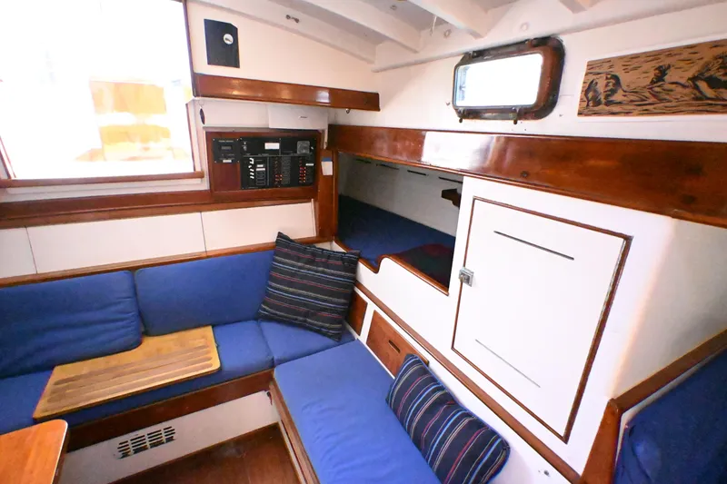 Slide: The Image of Cozy interior of a 1963 Rhodes 50 sailboat with blue seating and wooden accents. - 29