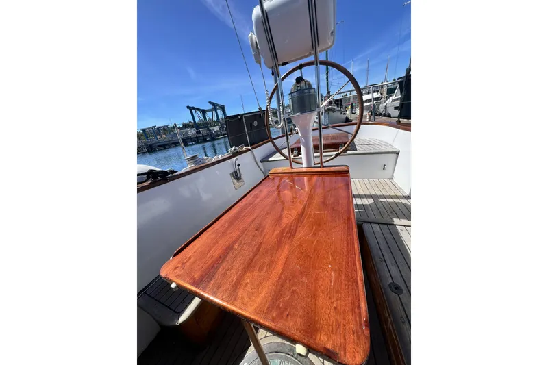 Slide: The Image of 1963 Rhodes 50 Cutter sailboat deck with wooden table and steering wheel. - 7