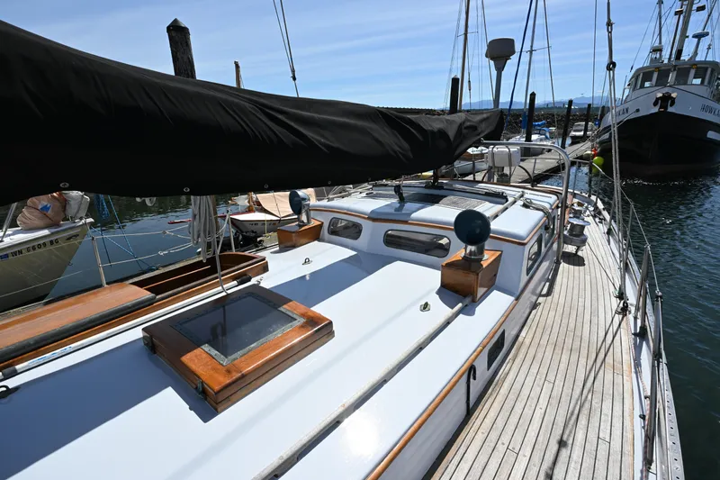 Slide: The Image of 1963 Rhodes 50 sailboat docked, featuring wooden deck and covered boom. - 18