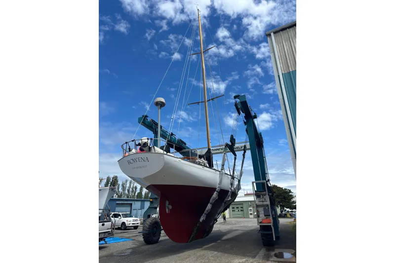 Slide: The Image of 1963 Rhodes 50 Cutter sailboat being lifted by a crane in a boatyard. - 51