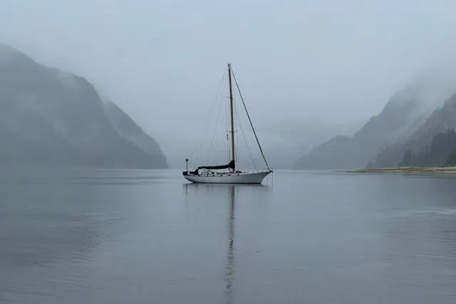 Slide: The Image of Sailboat "Rhodes 50 Cutter" from 1963 on misty lake with mountainous backdrop. - 56