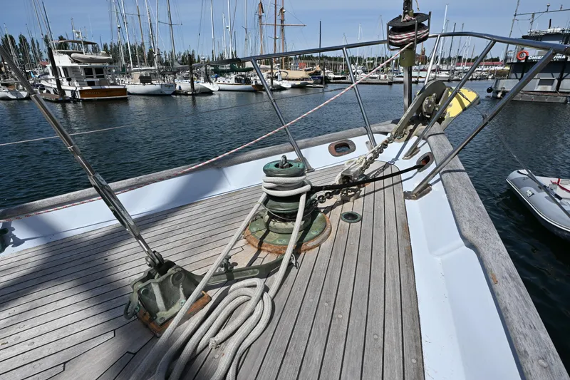 Slide: The Image of Deck view of a 1963 Rhodes 50 Cutter sailboat in a marina. - 14