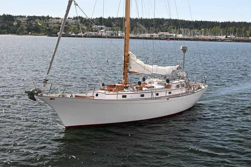 Slide: The Image of Vintage 1963 Rhodes 50 sailboat on calm water, with scenic shoreline background. - 2