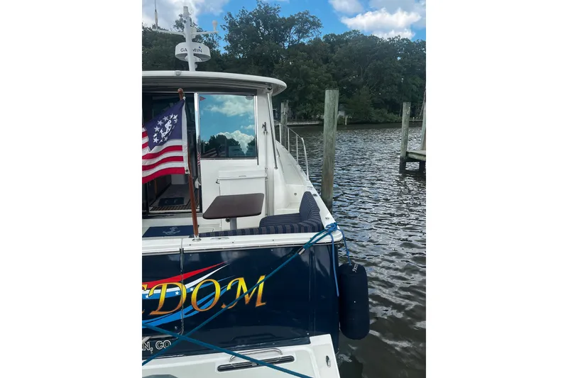 Slide: The Image of 2018 Back Cove 41 yacht docked, displaying an American flag, with serene water and trees. - 3