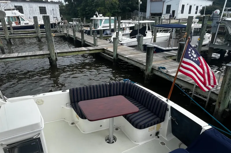 Slide: The Image of 2018 Back Cove 41 yacht docked, featuring a cozy seating area with a table and American flag. - 2