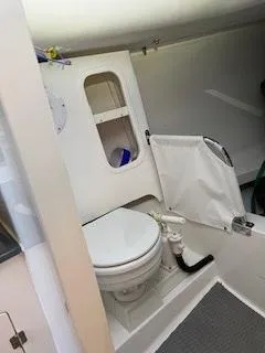 Slide: The Image of The image shows a compact boat toilet with white walls and a small shelf. - 16