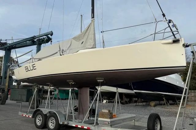 Slide: The Image of 2015 J Boats J/88 sailboat on trailer, named "Blue," in a boatyard setting. - 4