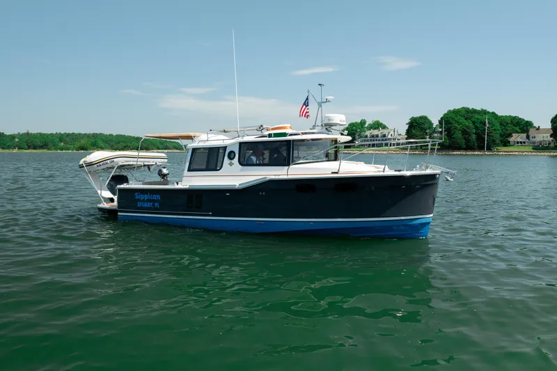 Slide: The Image of 2024 Ranger Tugs R-27 boat on calm water with scenic shoreline background. - 6