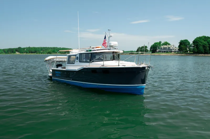 Slide: The Image of 2024 Ranger Tugs R-27 boat on calm water with scenic shoreline background. - 7
