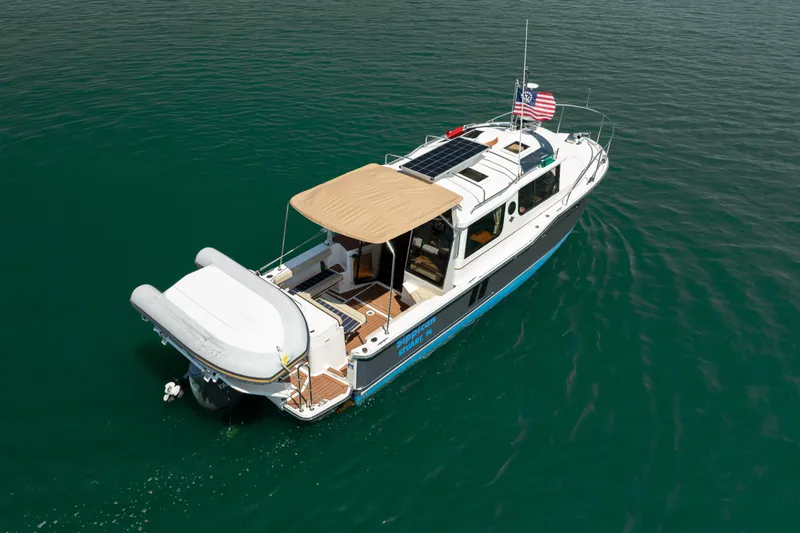 Slide: The Image of 2024 Ranger Tugs R-27 boat with canopy and solar panels on calm water. - 2