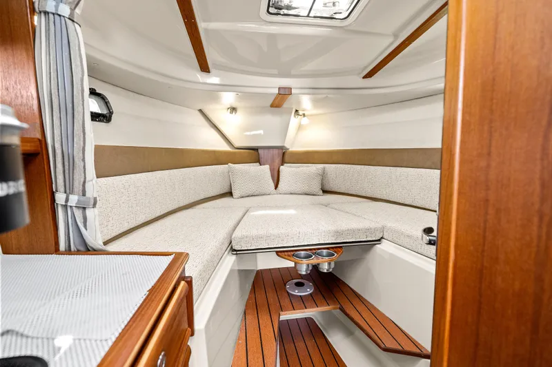 Slide: The Image of 2024 Ranger Tugs R-27 cabin interior with cozy seating and wooden accents. - 20