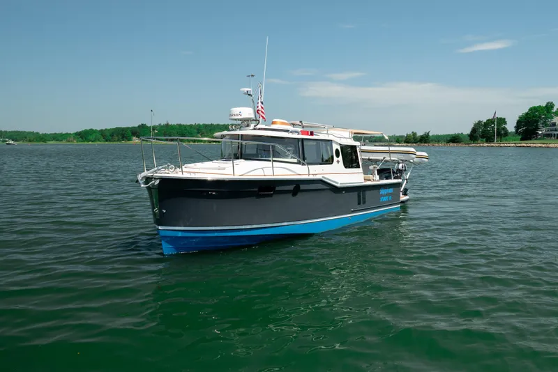 Slide: The Image of 2024 Ranger Tugs R-27 boat on calm water, clear sky background. - 11
