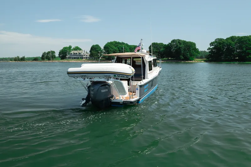 Slide: The Image of 2024 Ranger Tugs R-27 cruising on a serene lake with lush greenery. - 3