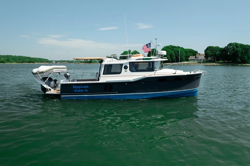 Slide: The Image of 2024 Ranger Tugs R-27 boat on calm water, displaying an American flag. - 5