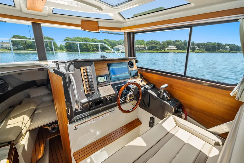Slide: The Image of 2024 Ranger Tugs R-27 helm with modern navigation equipment and scenic water view. - 15