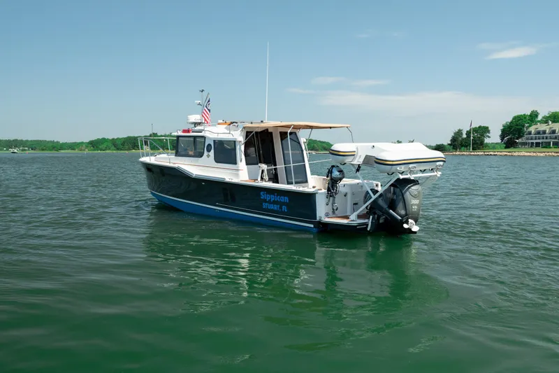 Slide: The Image of 2024 Ranger Tugs R-27 boat on calm water, featuring a sleek design and outboard motor. - 8