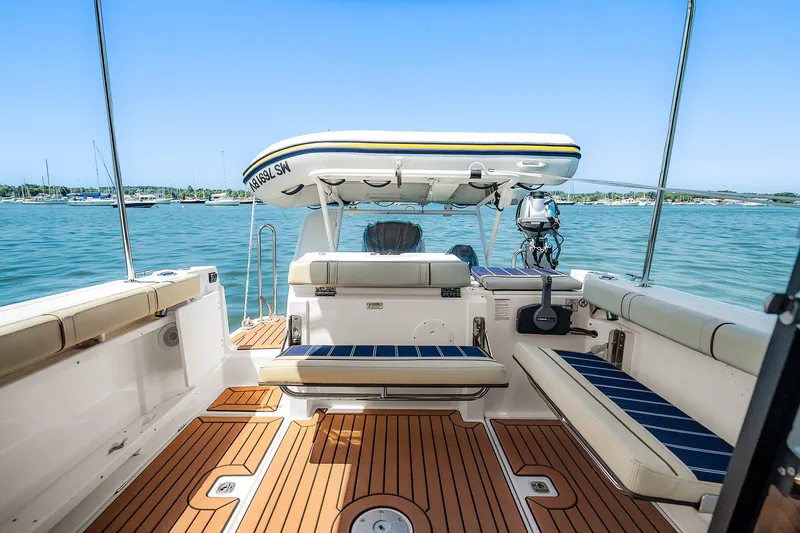 Slide: The Image of 2024 Ranger Tugs R-27 boat interior with seating, wood flooring, and ocean view. - 27