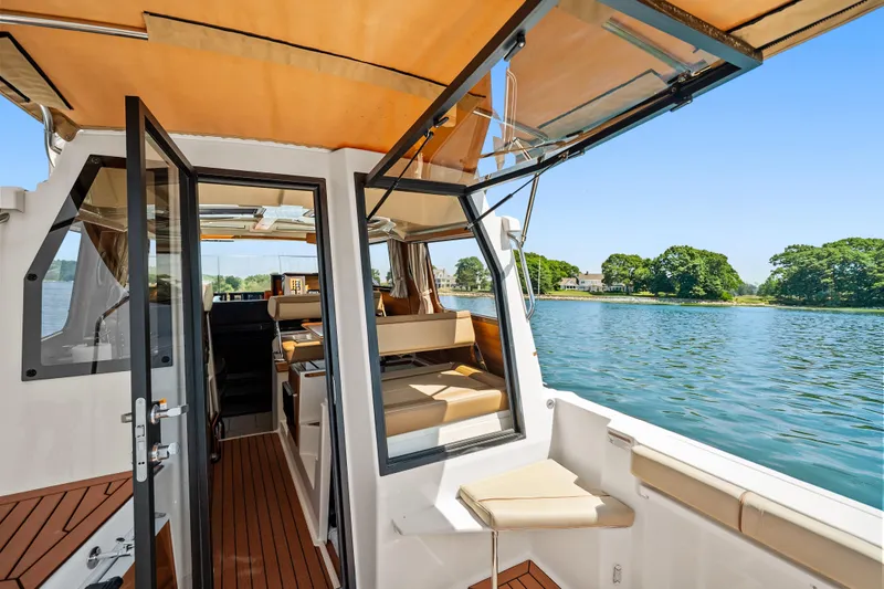 Slide: The Image of 2024 Ranger Tugs R-27 boat interior with open doors, scenic water view. - 22