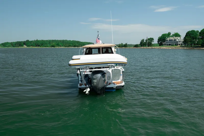 Slide: The Image of 2024 Ranger Tugs R-27 boat cruising on a serene lake with scenic shoreline. - 13