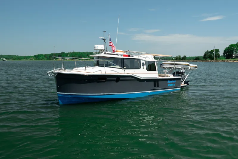 Slide: The Image of 2024 Ranger Tugs R-27 boat on calm water with American flag. - 10