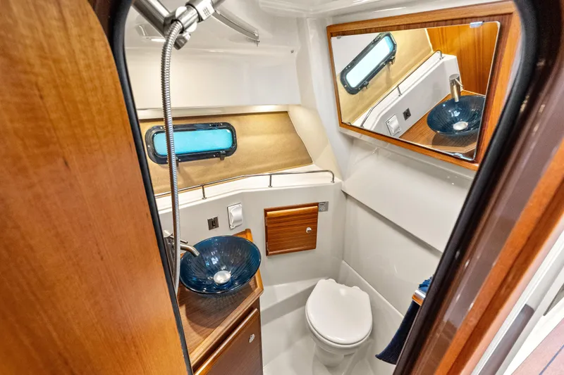 Slide: The Image of 2024 Ranger Tugs R-27 bathroom with modern sink, mirror, and compact design. - 21