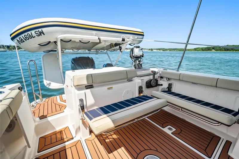 Slide: The Image of 2024 Ranger Tugs R-27 boat interior with seating and mounted dinghy on a sunny day. - 28