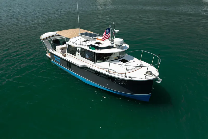 The Image of 2024 Ranger Tugs R-27 boat on calm water, featuring sleek design and American flag. - 0