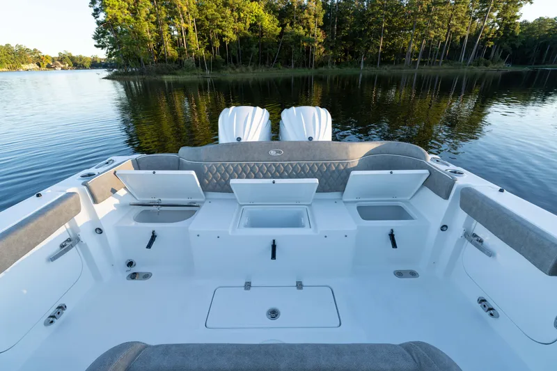 Slide: The Image of 2026 Sea Hunt Ultra 275 Coffin Box boat interior with open storage compartments on a serene lake. - 22