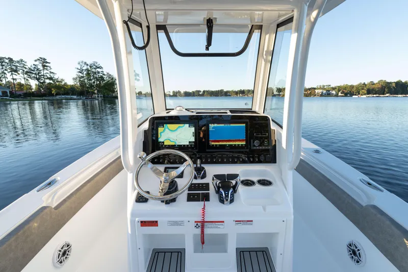 Slide: The Image of 2026 Sea Hunt Ultra 275 Coffin Box boat dashboard with navigation screens on a serene lake. - 27