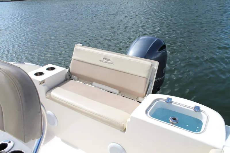 Slide: The Image of 2018 Cobia 220 Center Console boat with seating and outboard motor on water. - 17