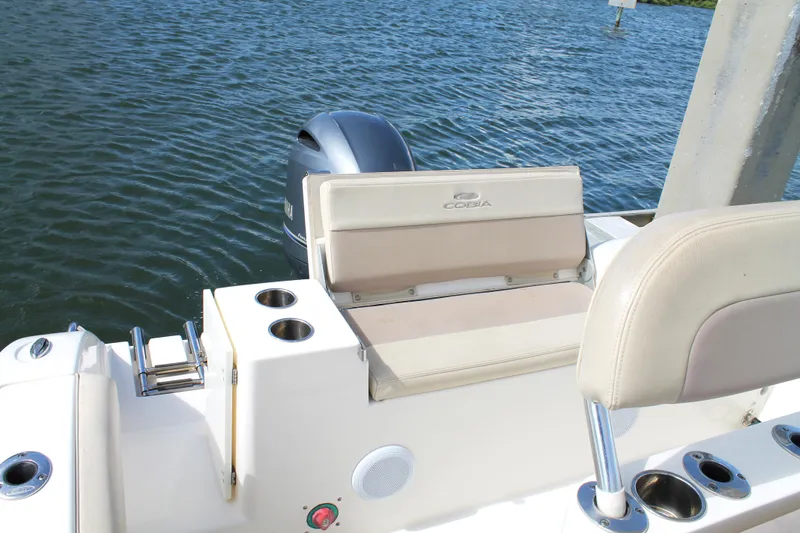 Slide: The Image of 2018 Cobia 220 Center Console boat with seating and cup holders on calm water. - 19